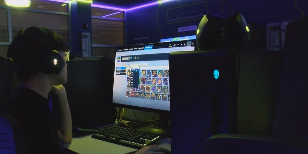 Student wearing headset playing at Alienware gaming PC in Launch Point lounge
