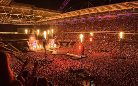 Packed stadium crowd at a Taylor Swift concert in London, with the stage lit up in the distance
