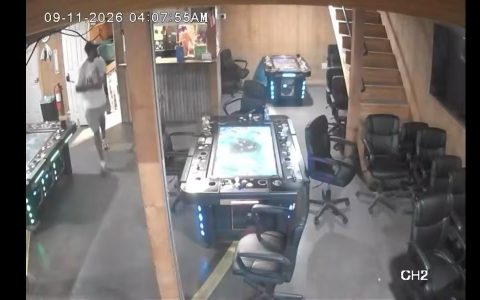 Interior of a game room showing electronic gaming tables and rows of office chairs, captured by a surveillance camera
