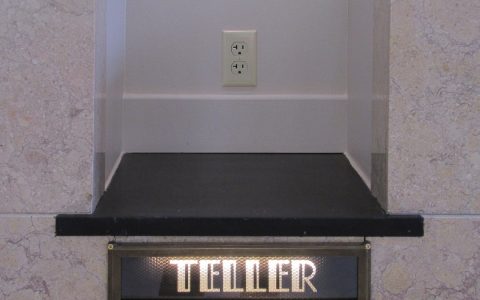 A bank teller window with a lit Teller sign