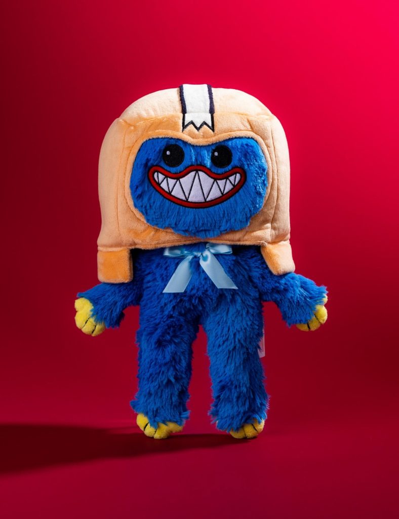 Front view of the Boxy x Huggy Wuggy plush: blue fur, a toothy grin, a light blue bow and an orange box-shaped head