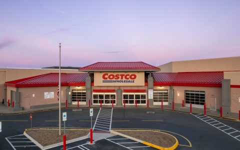 The front of a Costco Wholesale store with a red roof and an empty parking lot at dusk