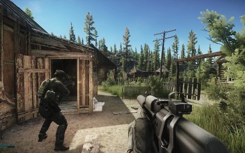 An armed player moves past a wooden shed in a forest, seen over another player's rifle