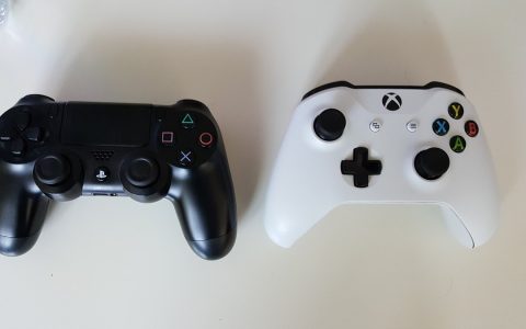 A PlayStation 4 controller and an Xbox One controller on a table