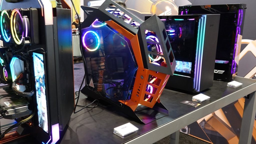 Several gaming PCs with glowing RGB fans displayed on a table