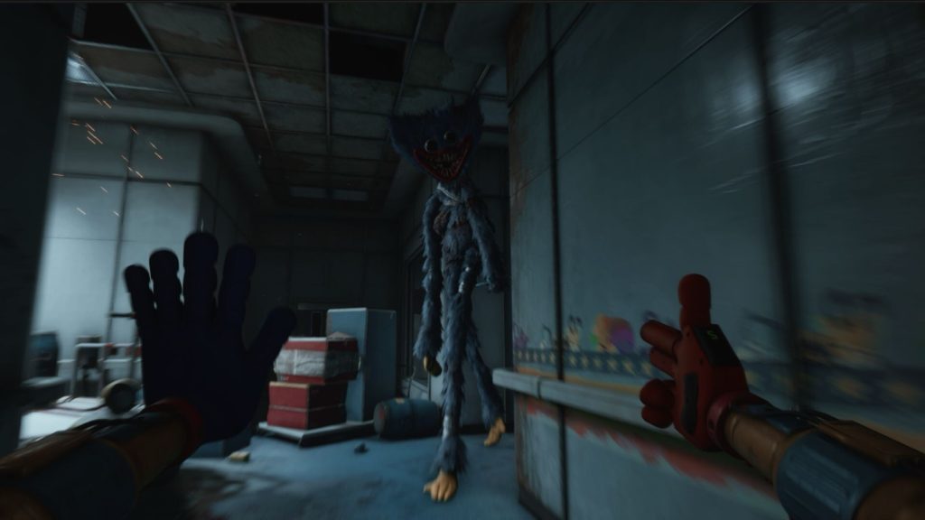 Huggy Wuggy standing in a damaged factory corridor, seen from first person with the GrabPack hands raised