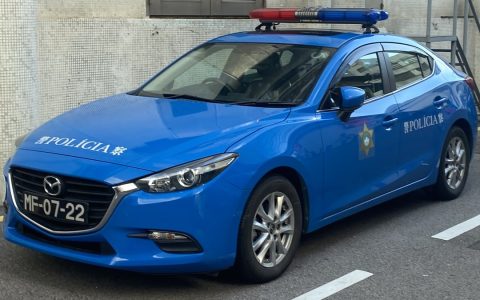 A blue Public Security Police patrol car parked on a street in Macau