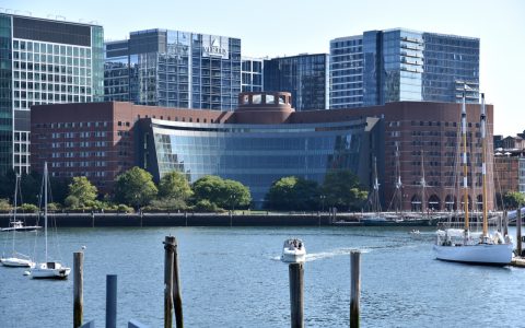 The John Joseph Moakley U.S. Courthouse in Boston, a brick building with a curved glass front, seen across the harbor