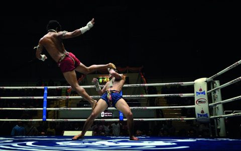 Muay Thai fighter leaps to kick his opponent in the ring at Lumpinee Boxing Stadium