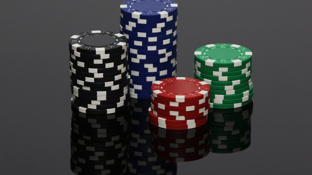 Stacks of black, blue, red and green poker chips on a reflective surface