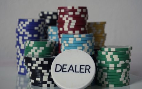 Stacks of colored poker chips behind a white dealer button