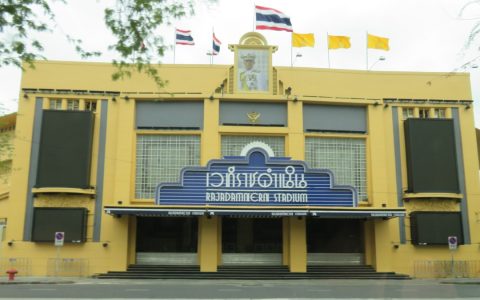 The yellow facade of Rajadamnern Stadium in Bangkok with its blue sign