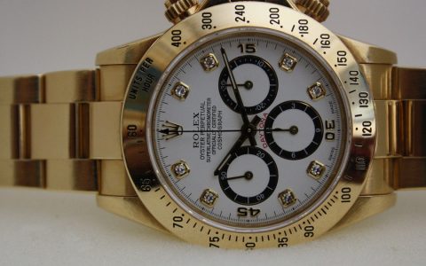 Close-up of a gold Rolex Daytona chronograph with a white dial and diamond hour markers