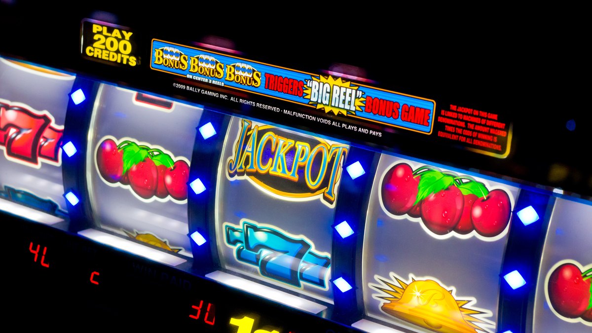 Close-up of lit slot machine reels showing cherries, sevens and a jackpot symbol