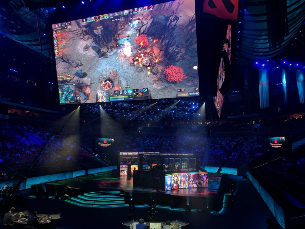 A packed KeyArena in Seattle during The International 2017, with a Dota 2 match on a giant screen above the stage