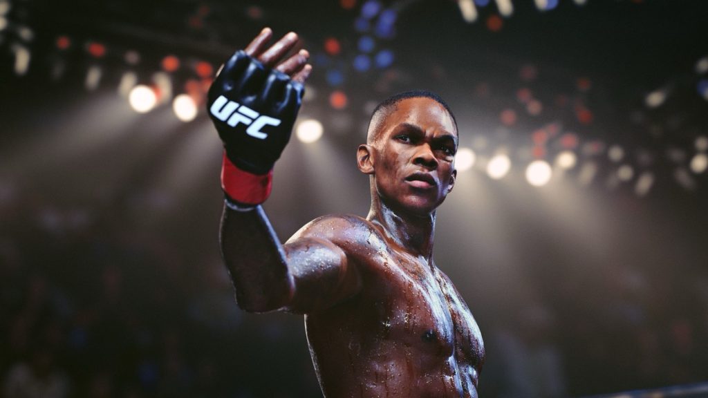 Israel Adesanya raises a gloved fist under arena lights