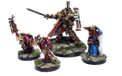Painted Warhammer 40,000 miniatures of an armored Inquisitor with a sword and four robed followers