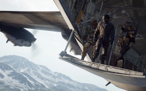 Soldiers in tactical gear stand on the open ramp of a cargo plane above snowy mountains